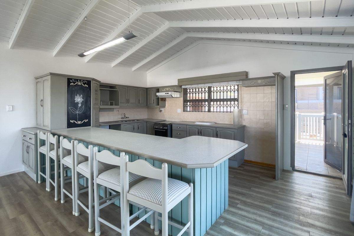 Spacious kitchen featuring a large breakfast bar, ample cabinetry, vaulted ceilings, and direct access to an outdoor patio area.