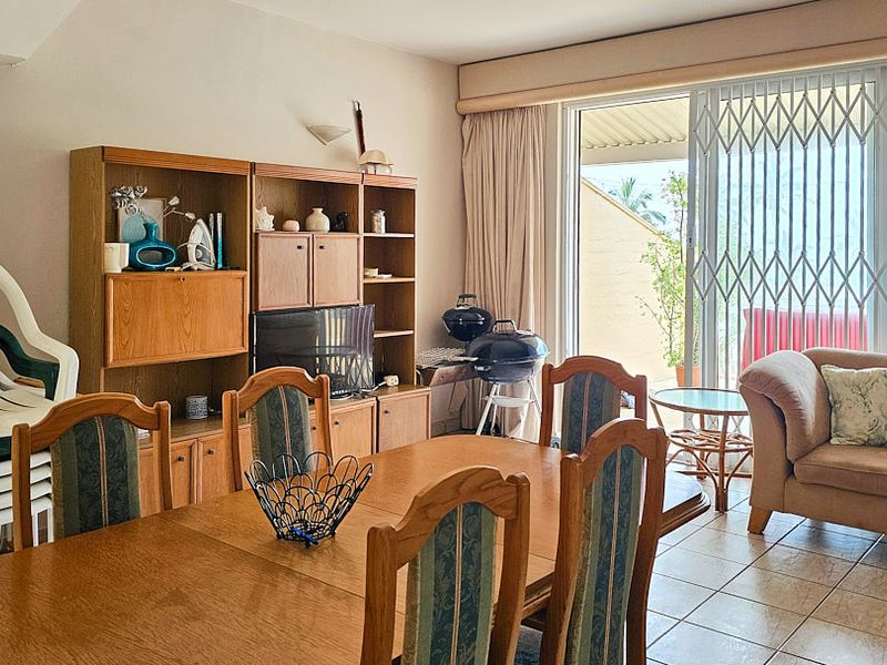 Open plan living and dining area featuring tiled flooring and a sliding glass door with a security gate leading to an outdoor space.