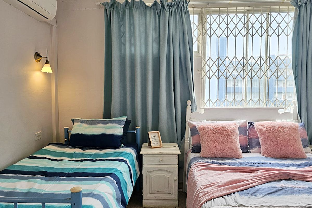 A bedroom featuring a split-system air conditioner, wall-mounted lighting, and a window secured with a metal security gate.