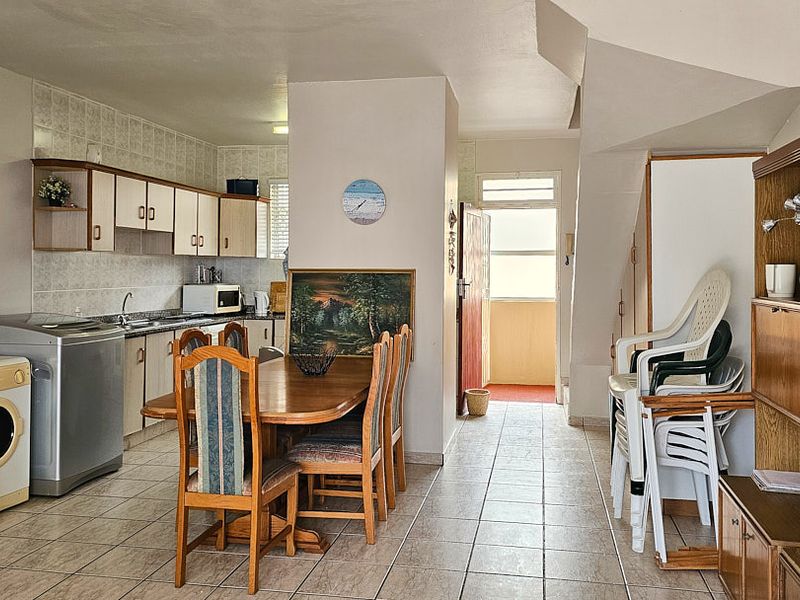 Open-plan living and kitchen area featuring tiled flooring, functional cabinetry, and direct access to the building entrance.