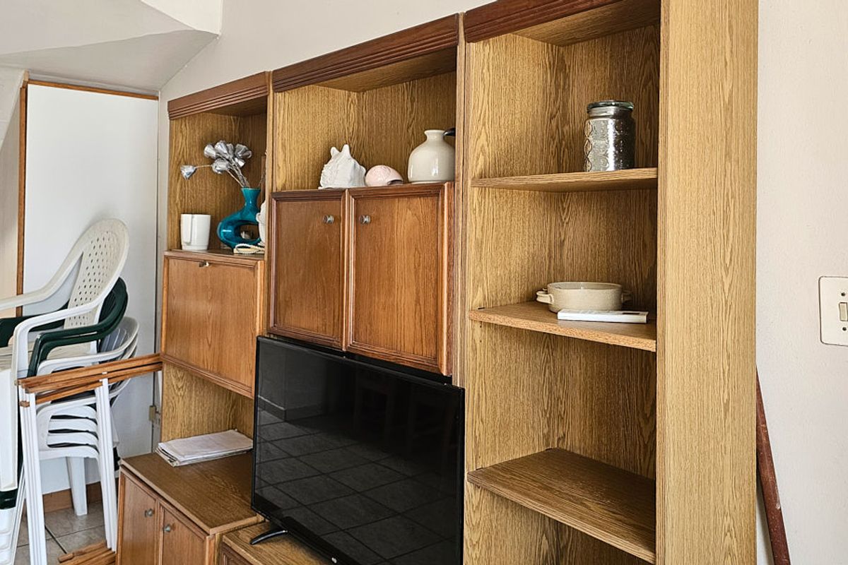 Living area featuring built-in wooden cabinetry and tiled flooring, providing functional storage space within the apartment.