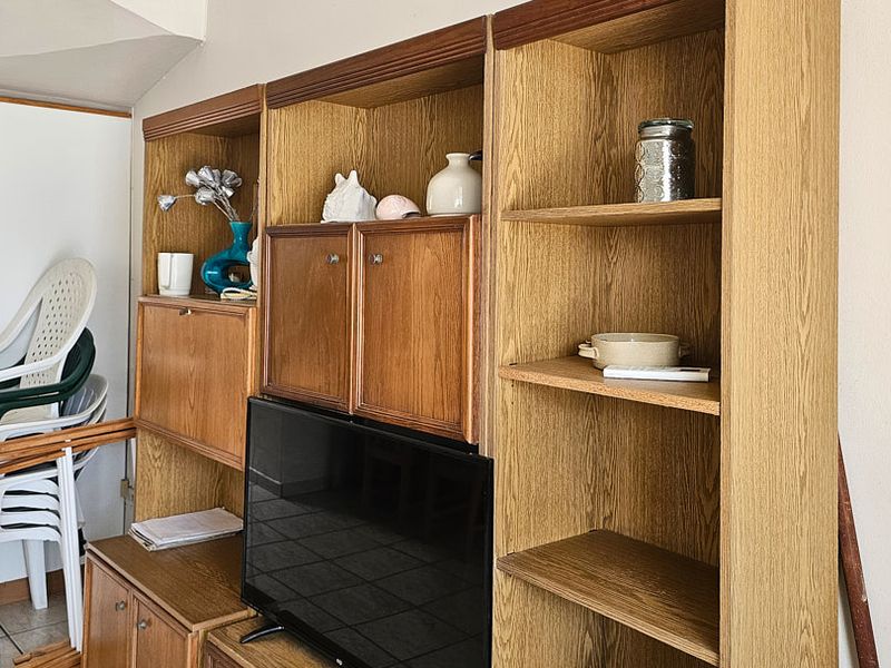 Living area featuring built-in wooden cabinetry and tiled flooring, providing functional storage space within the apartment.