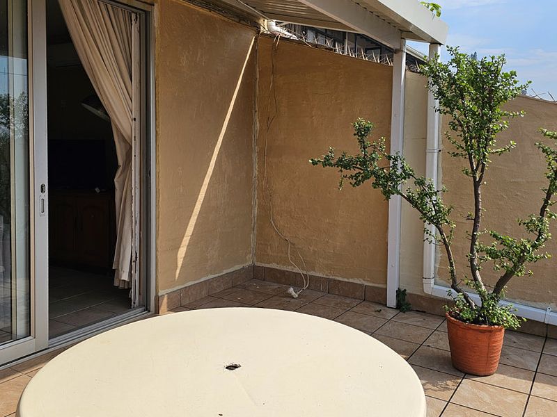 A covered balcony area featuring tiled flooring and sliding glass door access to the interior living space.