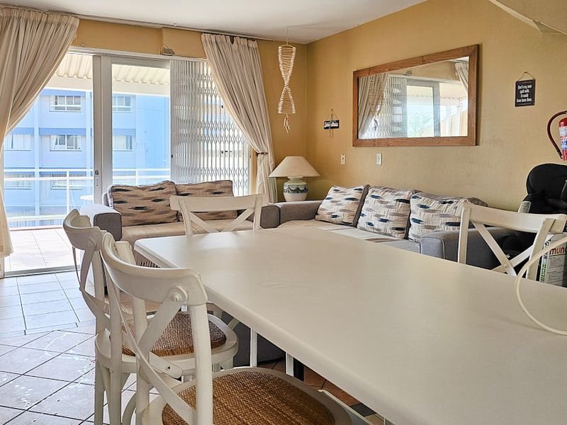 Open-plan living and dining area featuring tiled flooring and a sliding glass door leading to a balcony.