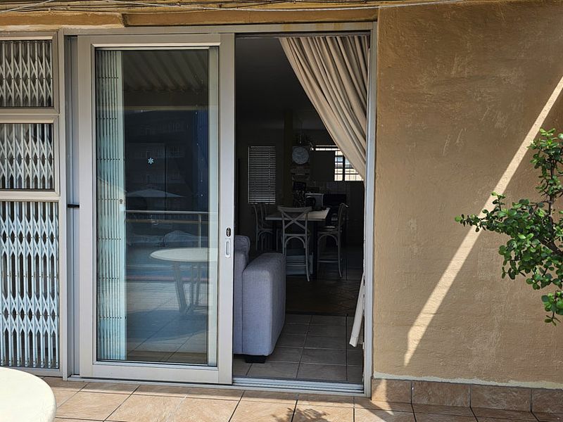 A balcony area featuring tiled flooring, a sliding glass door with a security gate, and access to the interior living space.