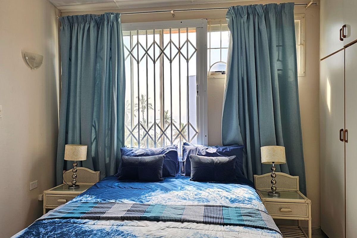 A bedroom featuring a built-in wardrobe, security gate on the window, and wall-mounted lighting.