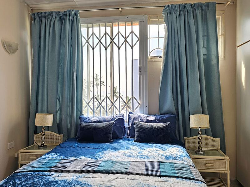 A bedroom featuring a built-in wardrobe, security gate on the window, and wall-mounted lighting.