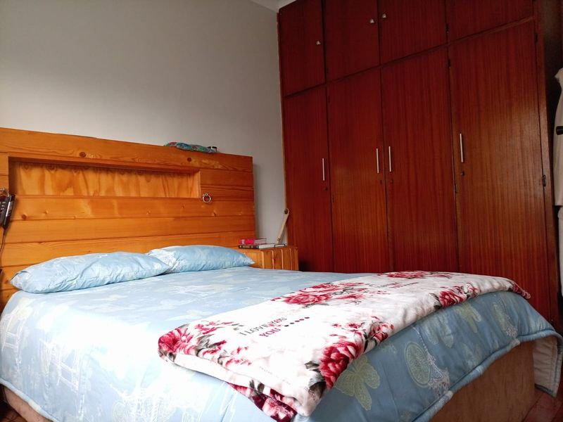 A bedroom featuring floor-to-ceiling built-in wooden cupboards and a matching wooden headboard.