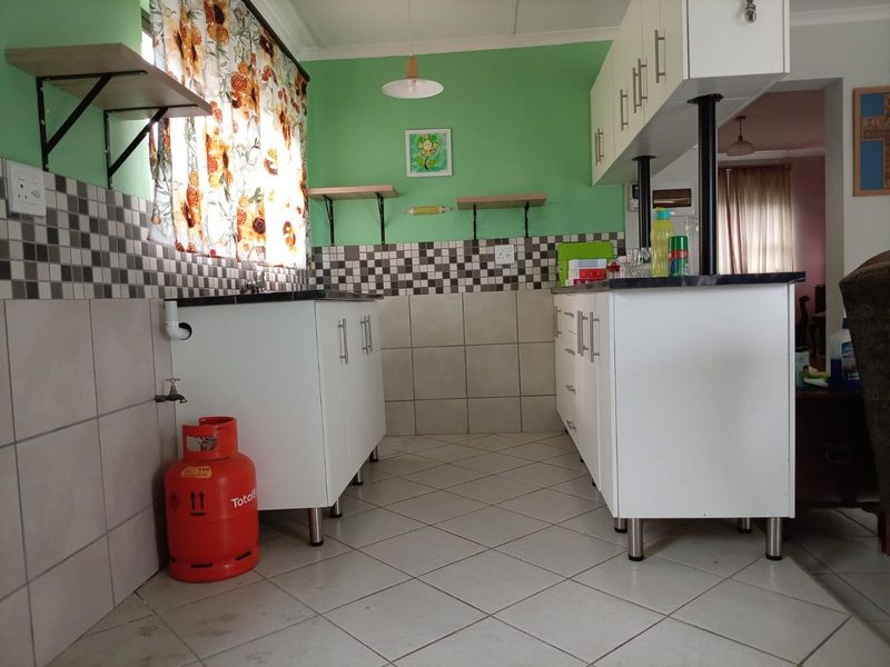 A functional kitchen featuring white built-in cabinetry, tiled backsplash, and tiled flooring with a practical layout.