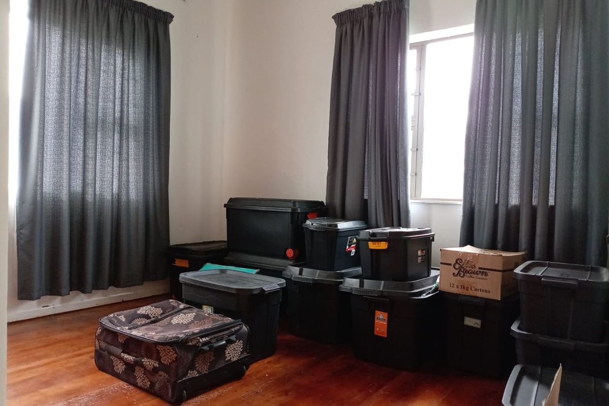 A vacant bedroom featuring timber flooring and dual windows with curtain tracks, offering a blank canvas for potential interior design updates.