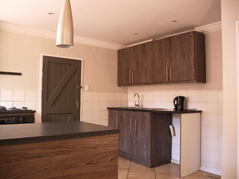 Kitchen featuring dark wood-look cabinetry, laminate countertops, tiled backsplash, and built-in stove, with a functional layout and neutral wall finishes.