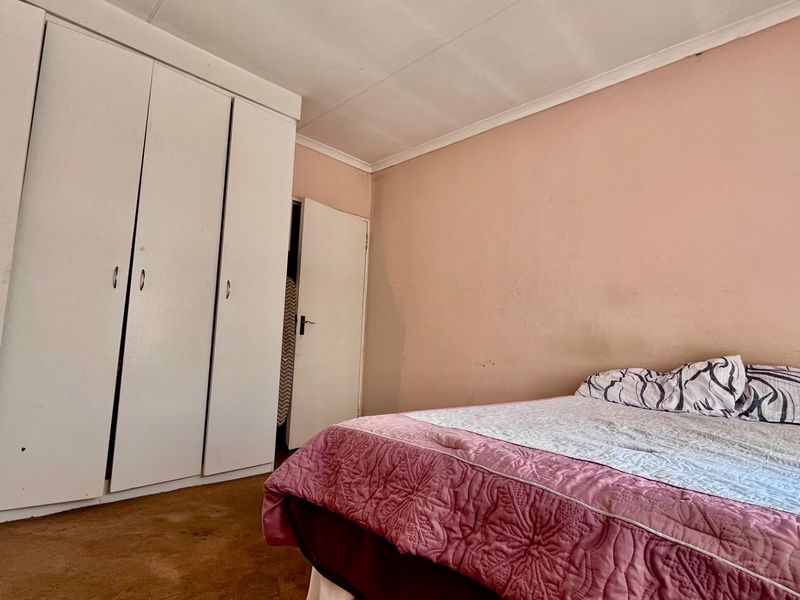A bedroom featuring built-in cupboards, coved ceilings, and carpeted flooring. The room requires cosmetic updates to the walls and flooring.