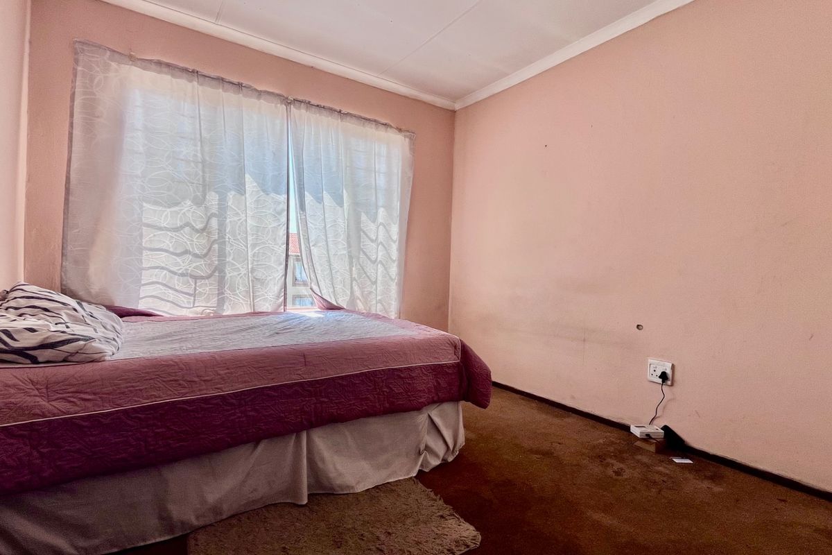 A bedroom featuring carpeted flooring and wall-mounted electrical outlets, requiring cosmetic updates to the wall finishes and flooring.