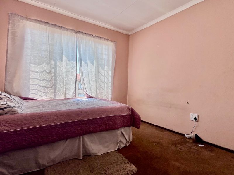 A bedroom featuring carpeted flooring and wall-mounted electrical outlets, requiring cosmetic updates to the wall finishes and flooring.