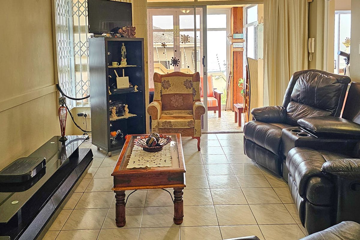 A living room featuring ceramic floor tiles and a sliding glass door providing access to an outdoor patio area.