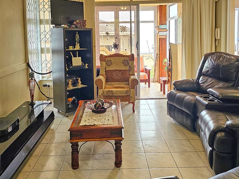 A living room featuring ceramic floor tiles and a sliding glass door providing access to an outdoor patio area.