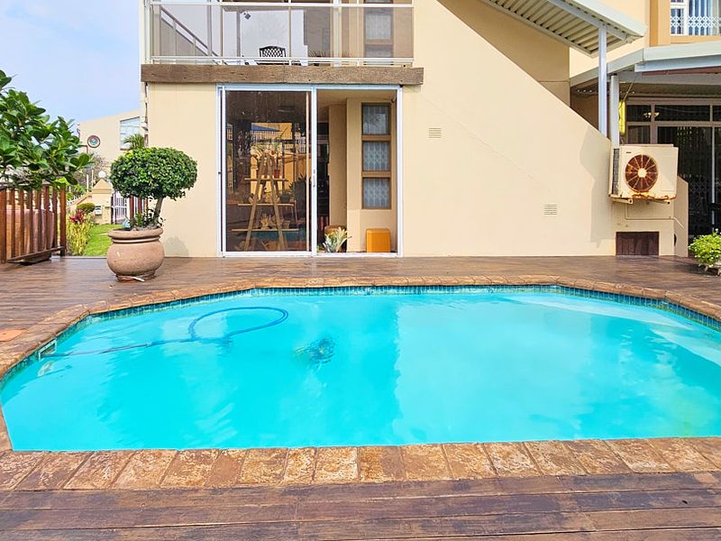 Outdoor pool area featuring timber decking, a swimming pool, and direct access to the residence via sliding glass doors.