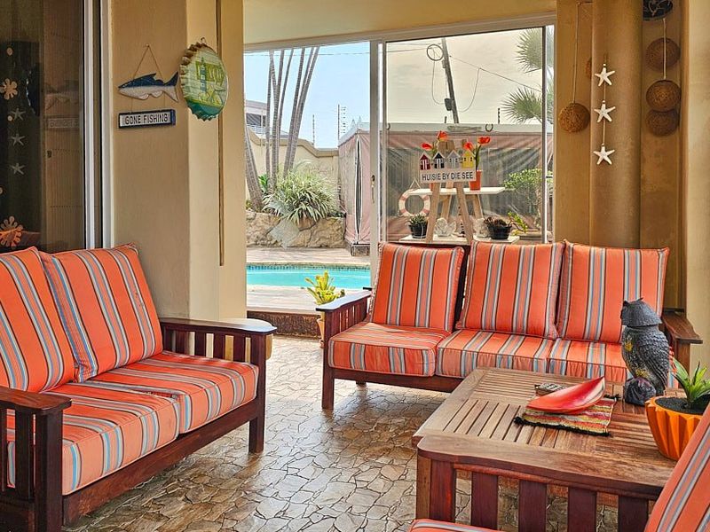 A covered patio area featuring tiled flooring and sliding glass doors, providing direct access to the outdoor pool area.