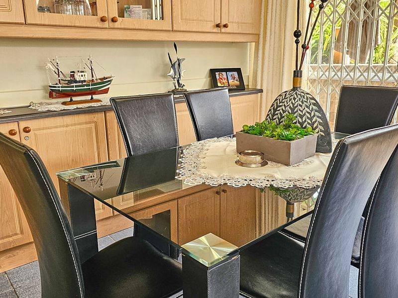 Dining area featuring built-in wooden cabinetry and tiled flooring, with direct access to an outdoor area through a security gate.