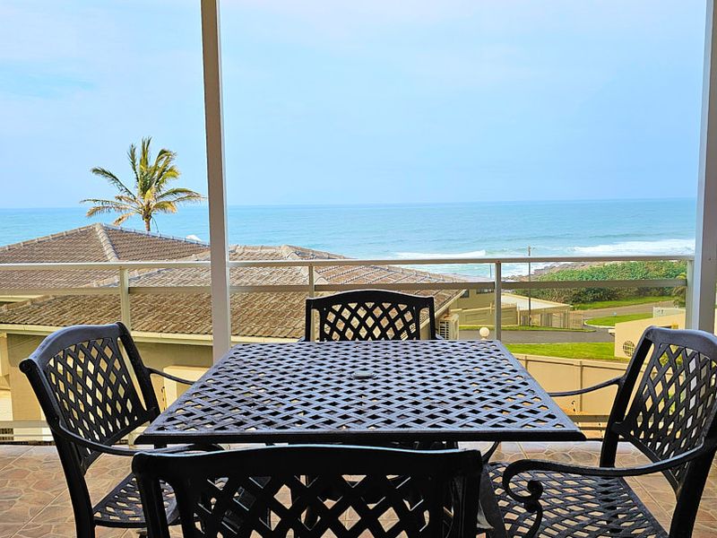 A covered balcony featuring tiled flooring and a metal balustrade, offering expansive ocean views.