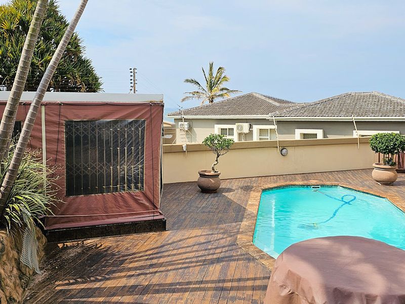 Outdoor pool area featuring timber decking, a swimming pool, and a retractable awning, providing a private space for relaxation and entertainment.