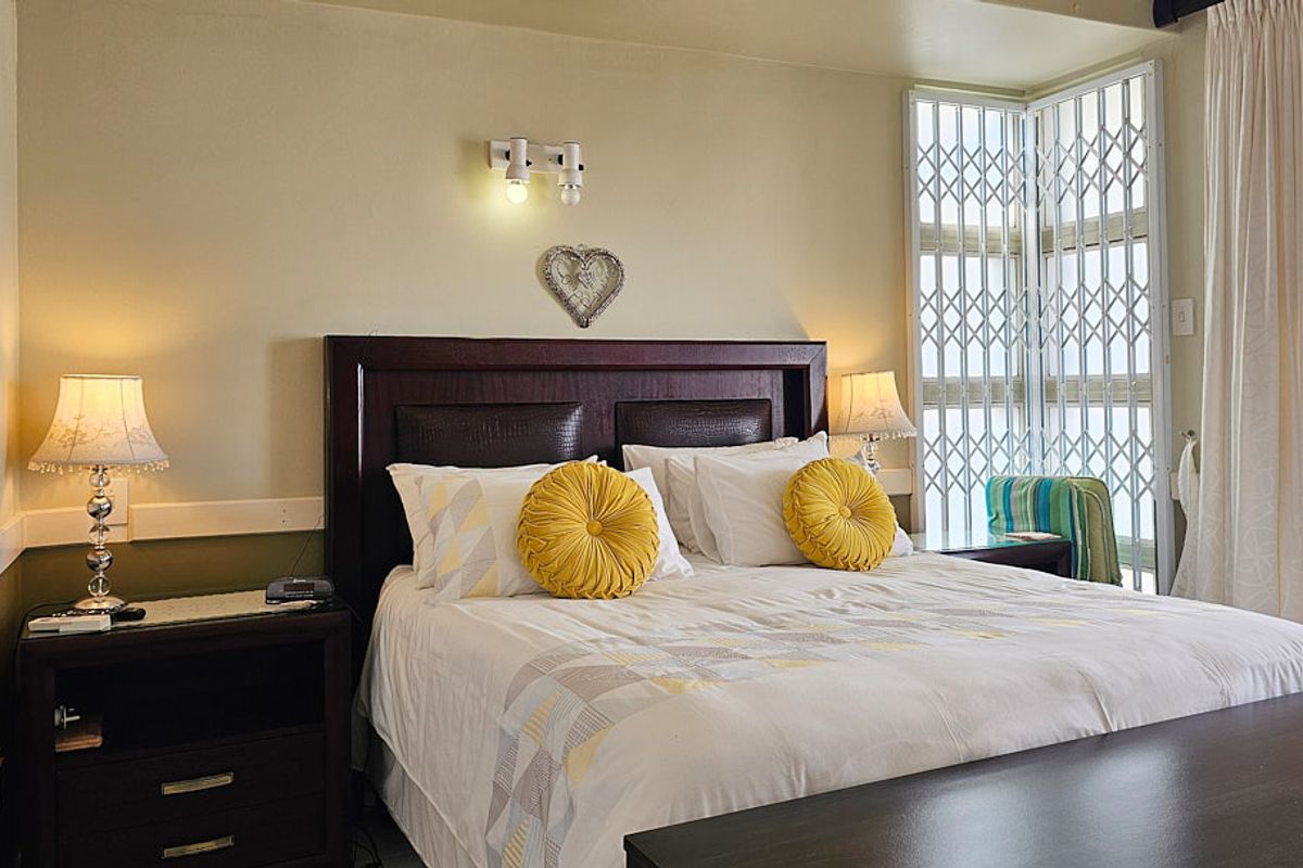 A comfortable bedroom featuring a large window with a fitted security gate, providing natural light and secure access to the exterior.