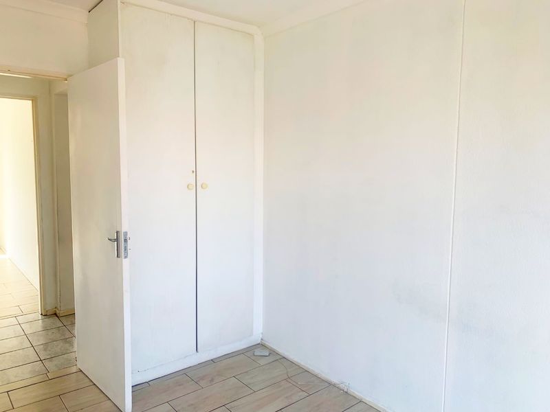 An empty bedroom featuring tiled flooring and a built-in cupboard, presenting a blank canvas for potential interior design updates.