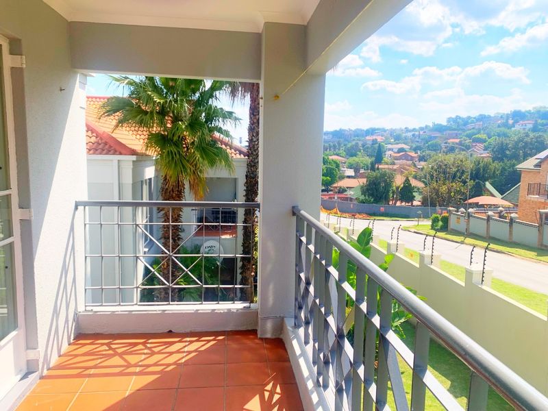 A covered balcony featuring tiled flooring and a metal balustrade, offering an elevated view of the surrounding neighborhood.