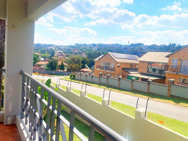 A covered balcony featuring a metal balustrade and tiled flooring, offering an elevated view of the surrounding residential neighbourhood and street.