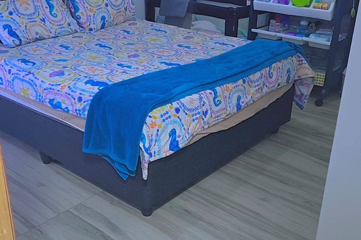A bedroom featuring light-toned laminate flooring and neutral wall finishes.