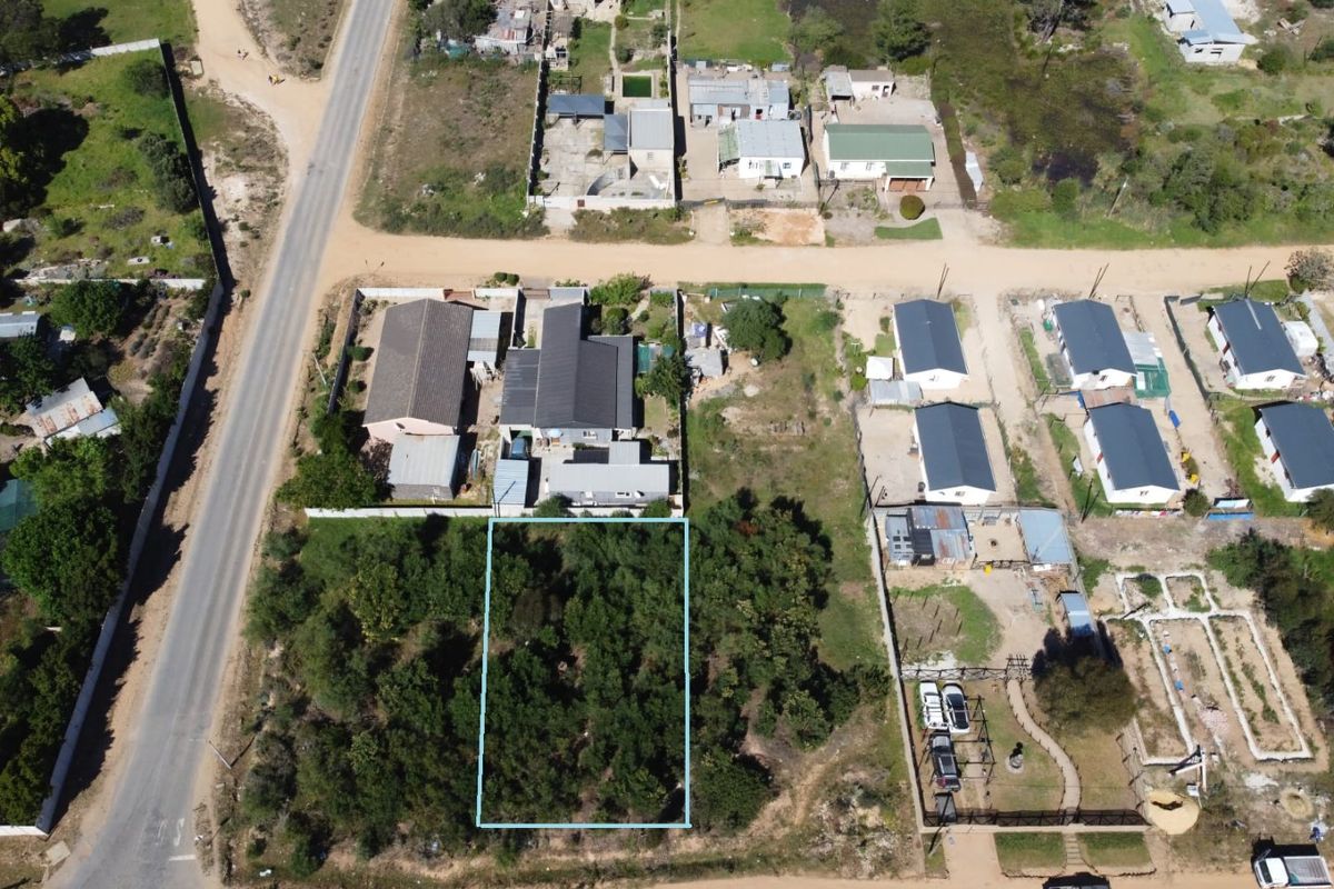 An aerial view of a vacant residential plot featuring dense vegetation, situated within an established neighborhood with access to local road infrastructure.