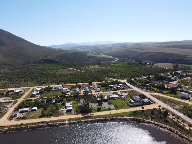 An aerial view of the residential area, showcasing the surrounding landscape, nearby water body, and proximity to mountainous terrain.