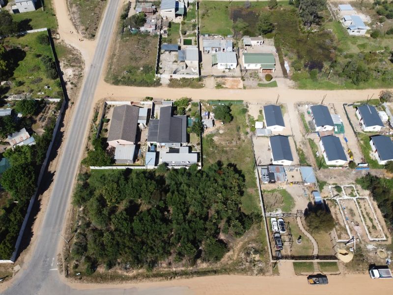 An aerial view of a residential area showing vacant land plots, existing dwellings, and surrounding road infrastructure.