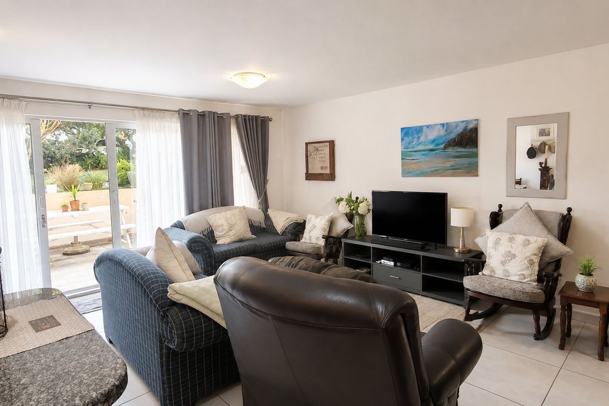 A comfortable living room featuring tiled flooring and a large sliding glass door that provides direct access to the outdoor patio area.
