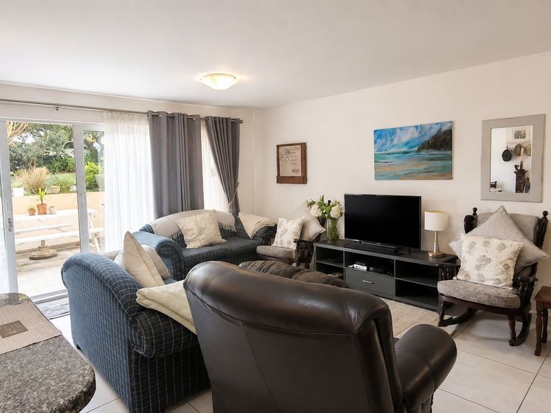 A comfortable living room featuring tiled flooring and a large sliding glass door that provides direct access to the outdoor patio area.