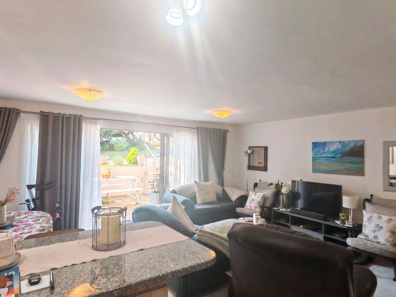 Open plan living area featuring a granite breakfast bar and large sliding glass doors providing direct access to the outdoor patio space.