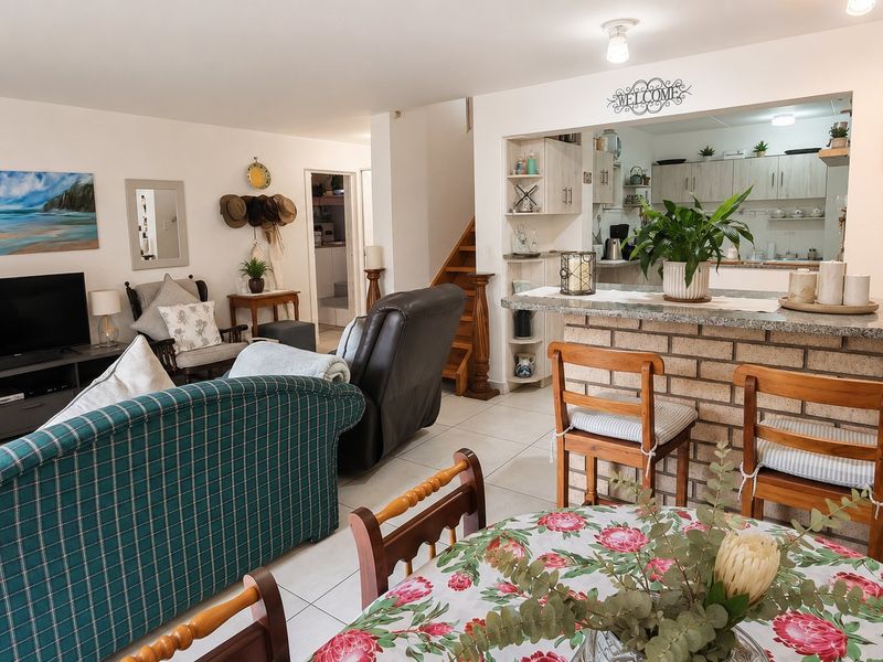 Open-plan living and dining area featuring a brick breakfast bar with granite countertop, tiled flooring, and a wooden staircase leading to the upper level.