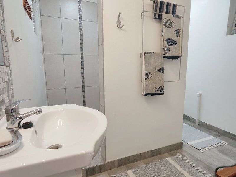A clean, modern bathroom featuring a vanity basin with chrome mixer tap, mosaic tile accents, and a tiled shower enclosure.