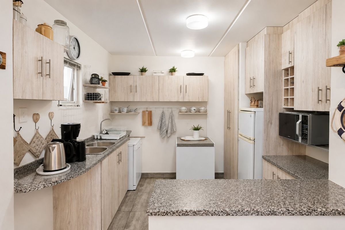 A functional kitchen featuring light wood-look cabinetry, granite countertops, a double basin sink, and built-in microwave, offering a clean and practical workspace.