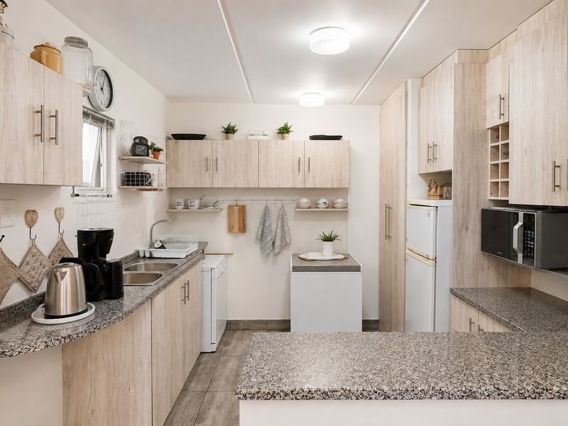 A functional kitchen featuring light wood-look cabinetry, granite countertops, a double basin sink, and built-in microwave, offering a clean and practical workspace.