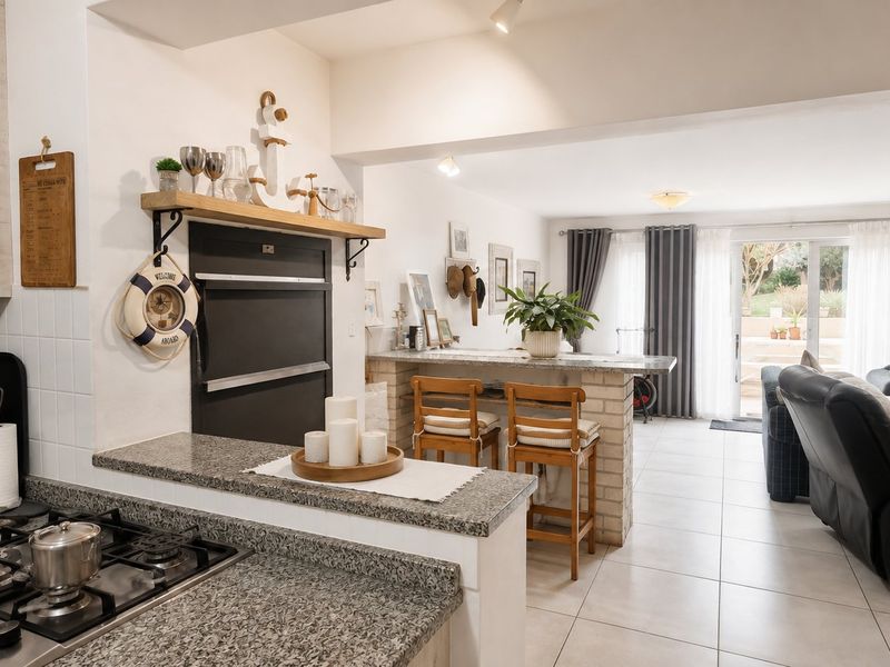 Open-plan kitchen and living area featuring granite countertops, a gas hob, breakfast bar, and direct access to the outdoor patio through sliding glass doors.