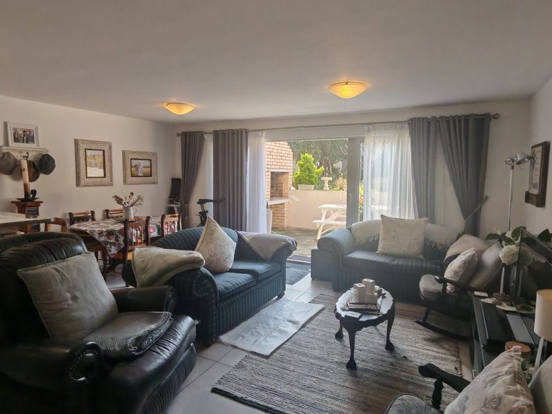 Open-plan living and dining area featuring tiled flooring and large sliding doors providing direct access to a rear patio with a built-in braai.