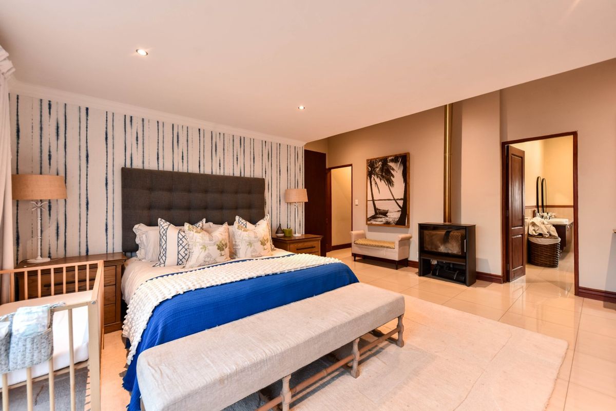 Spacious bedroom featuring tiled flooring, a modern freestanding fireplace, and direct access to an en-suite bathroom.