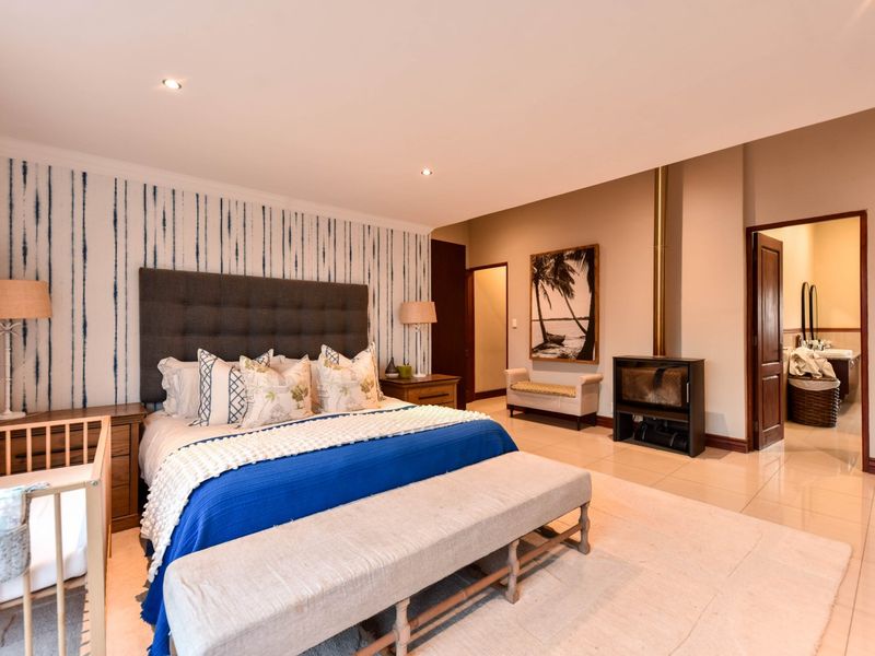 Spacious bedroom featuring tiled flooring, a modern freestanding fireplace, and direct access to an en-suite bathroom.