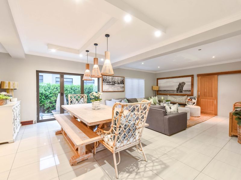 Spacious open-plan living and dining area featuring neutral tiled flooring, recessed ceiling lighting, and direct access to the outdoor space via sliding glass doors.
