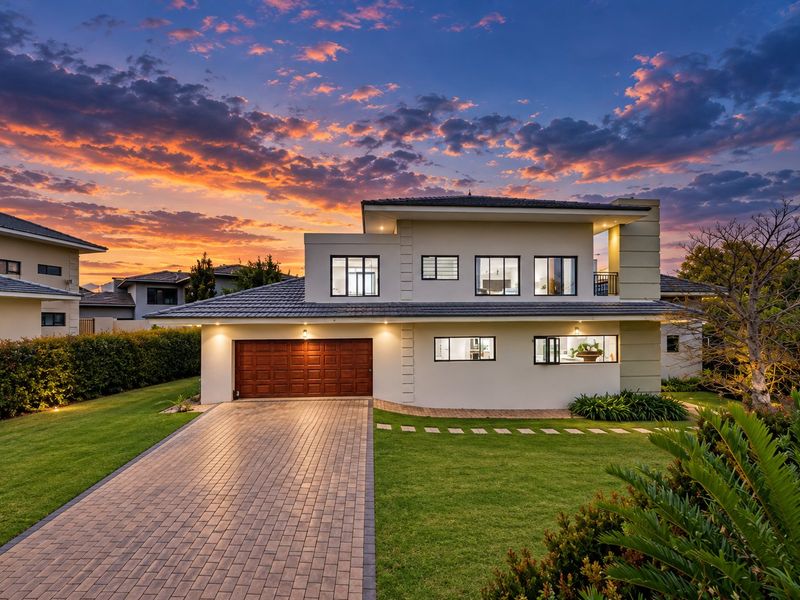 A beautifully presented double-story home featuring a paved driveway, double garage, and well-maintained garden, captured at sunset.