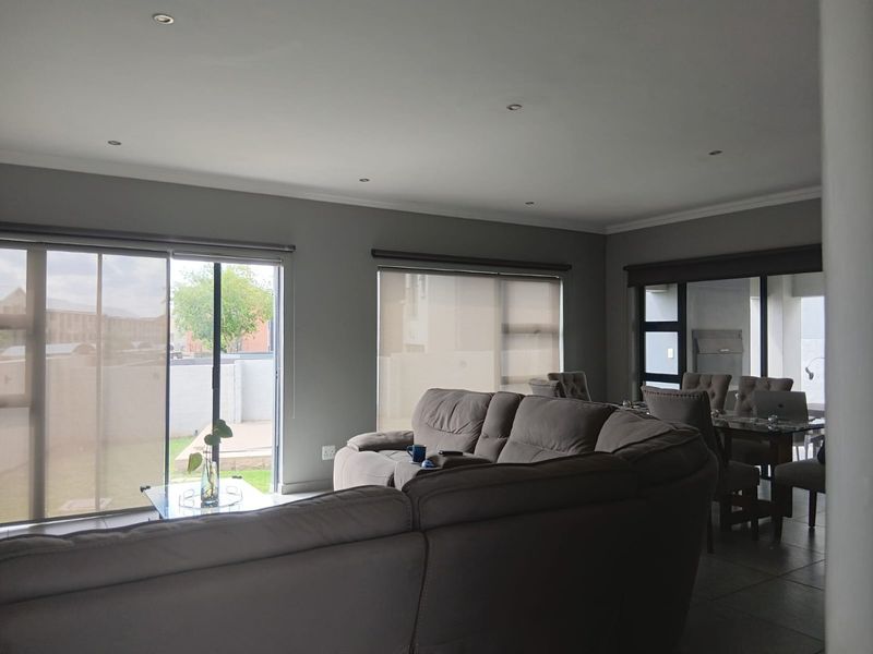 Spacious open-plan living and dining area featuring large sliding glass doors, neutral wall tones, recessed lighting, and tiled flooring throughout.