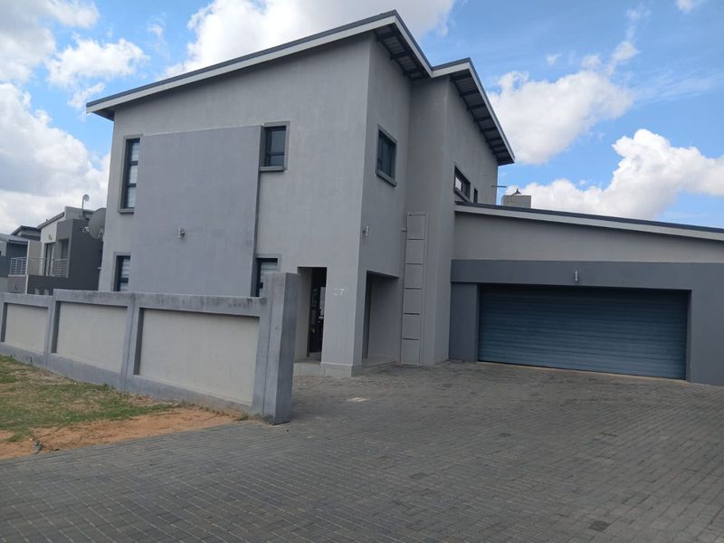 Modern double-story residential property featuring a paved driveway, double garage, and secure boundary walling.