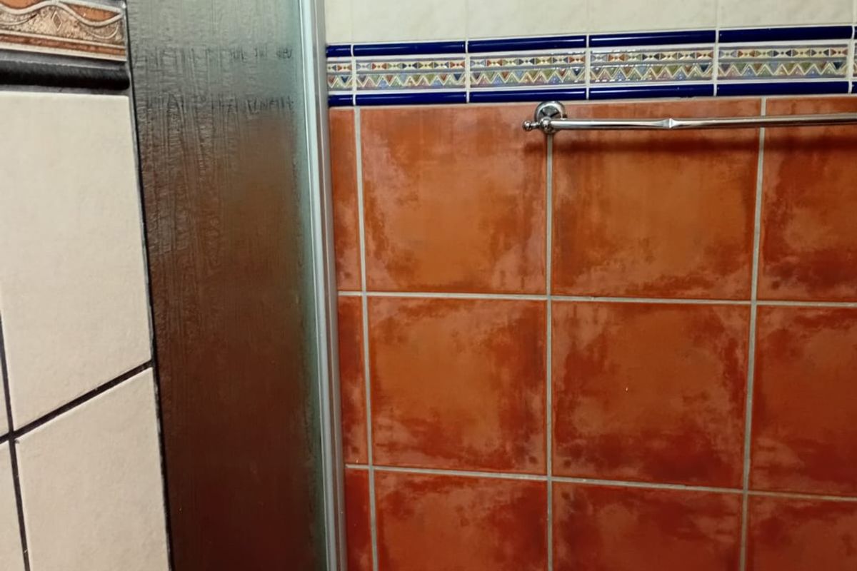 A bathroom featuring a shower enclosure with a glass door and decorative tiled walls with a towel rail.