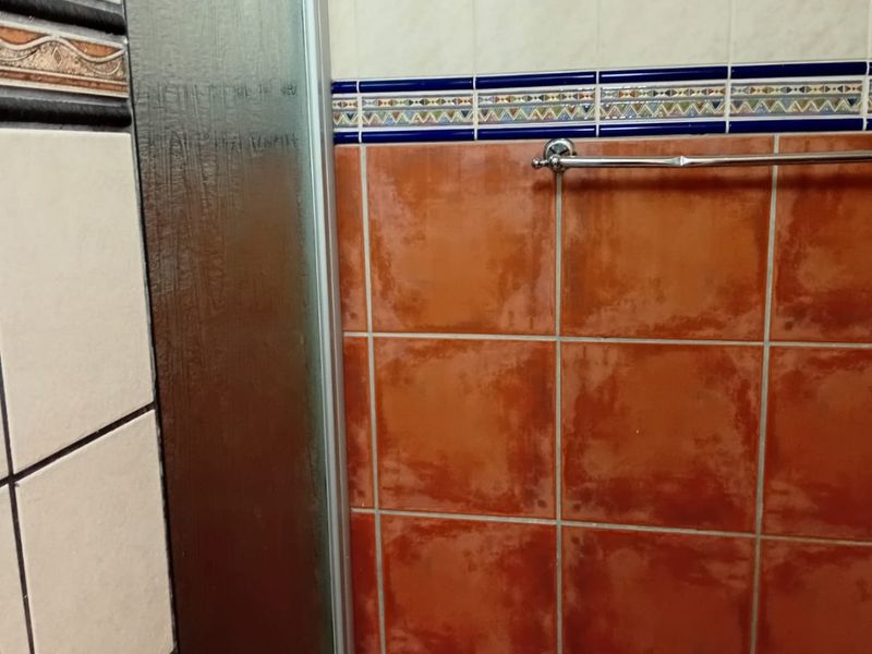 A bathroom featuring a shower enclosure with a glass door and decorative tiled walls with a towel rail.